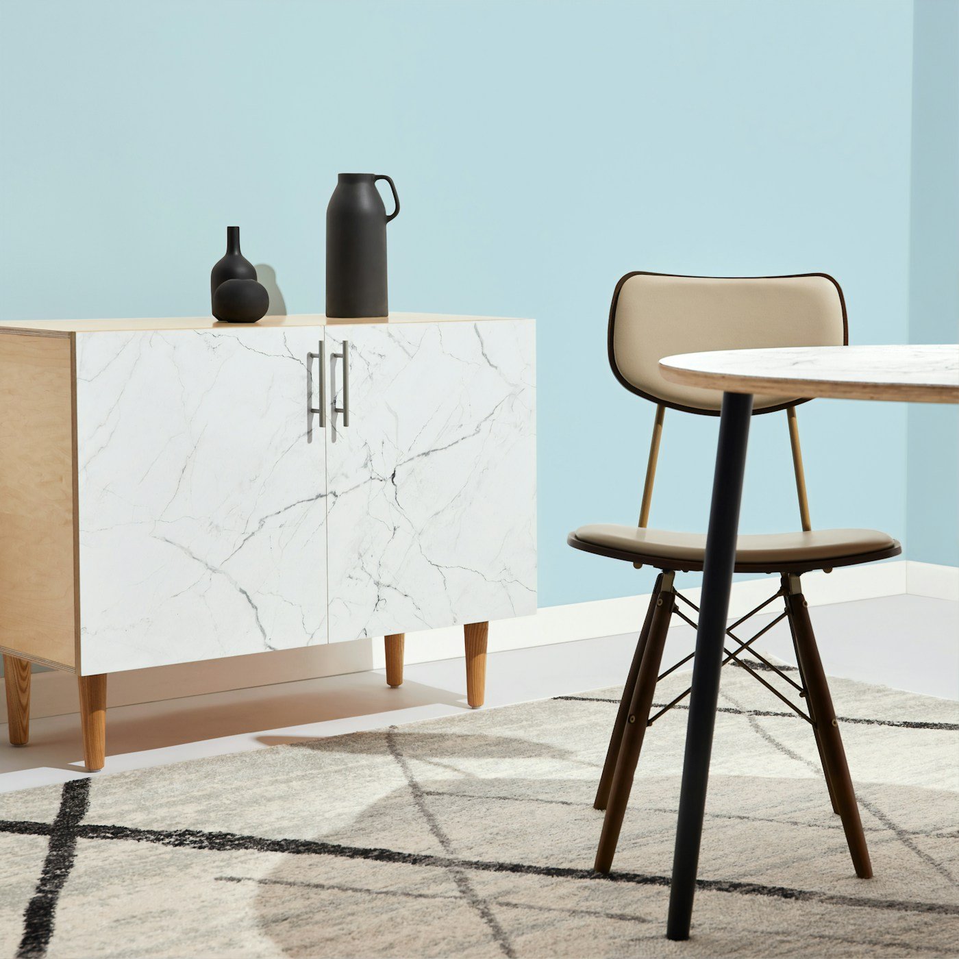 A marble-front cabinet, dining chair, and round table in a clean interior